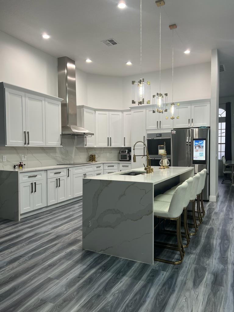 Renovated kitchen with white shaker cabinets and a marble backsplash