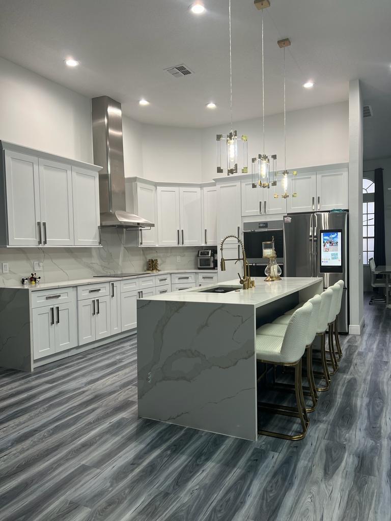 Renovated white kitchen with gold fixtures and a marble waterfall island