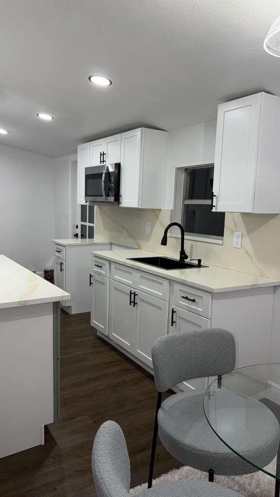 Remodeled white kitchen with matte black fixtures and quartz countertops